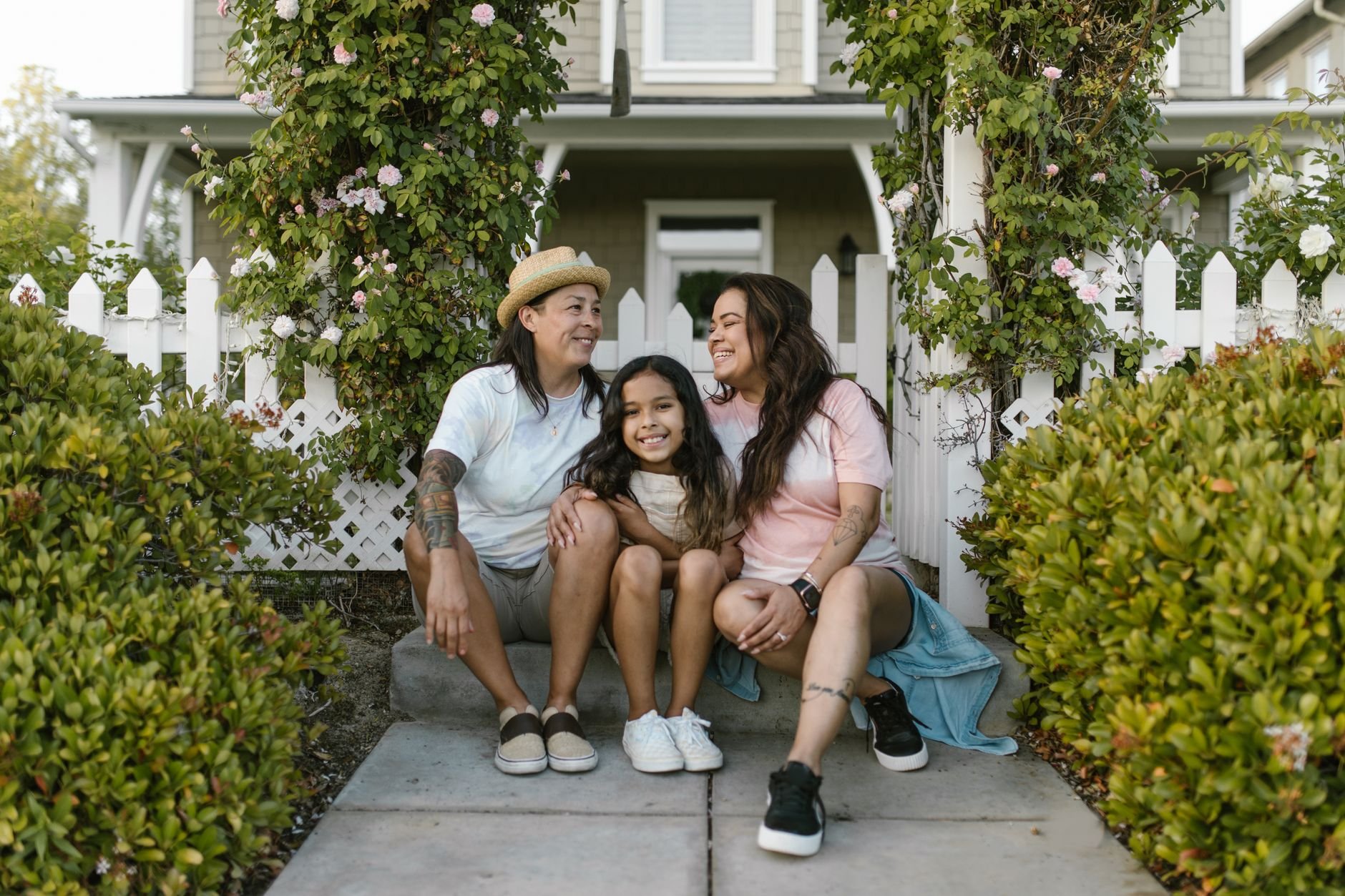 A joyful family of three sitting together outside their home, showing love and happiness.