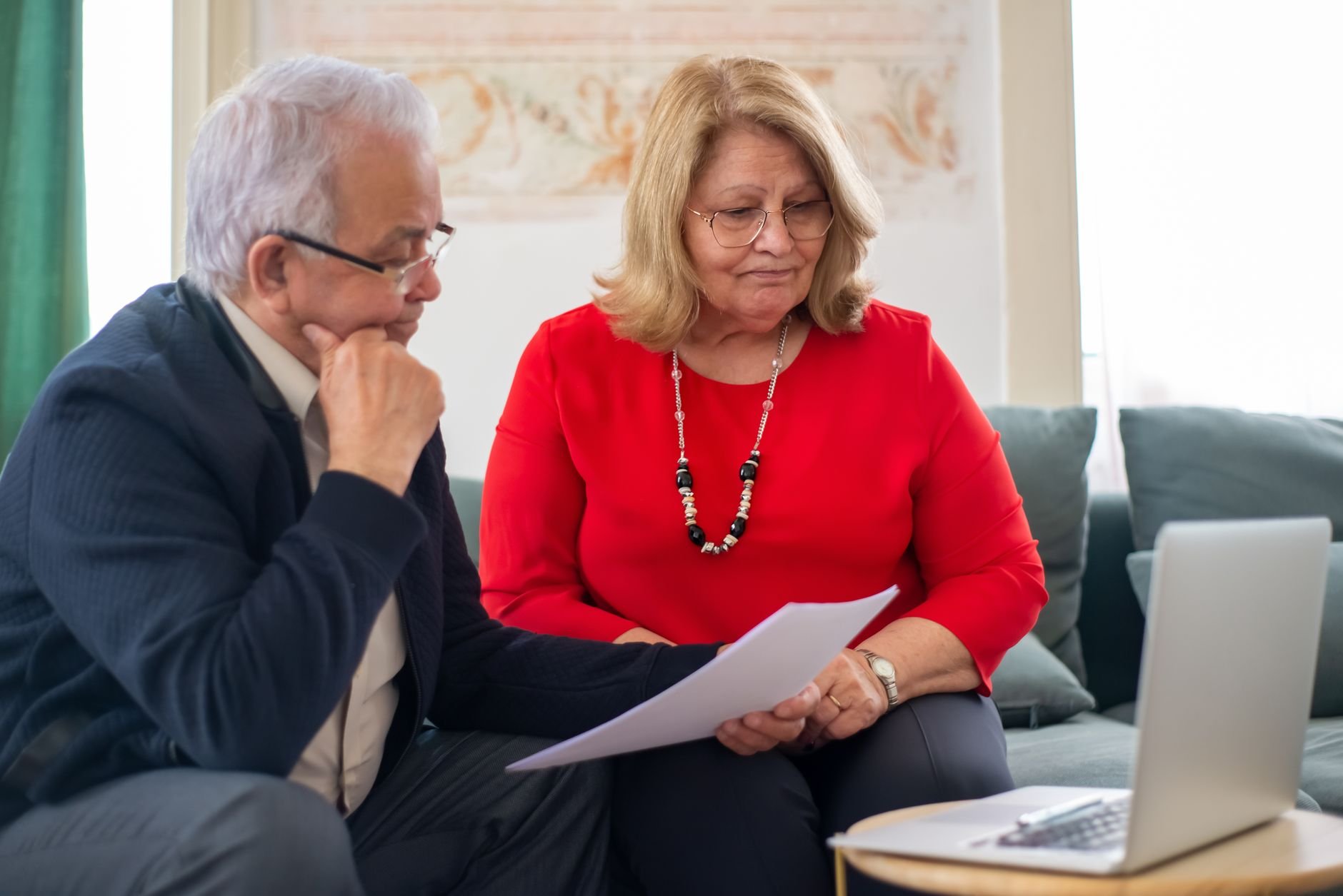 Elderly couple reviewing financial documents together at home.